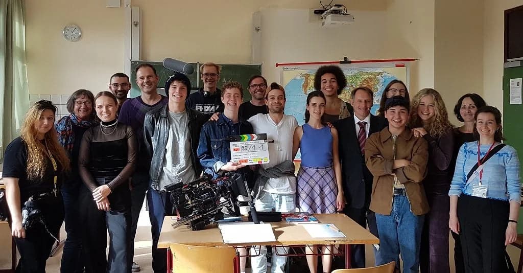 Cast and crew of FREE with a clapperboard on set in a classroom