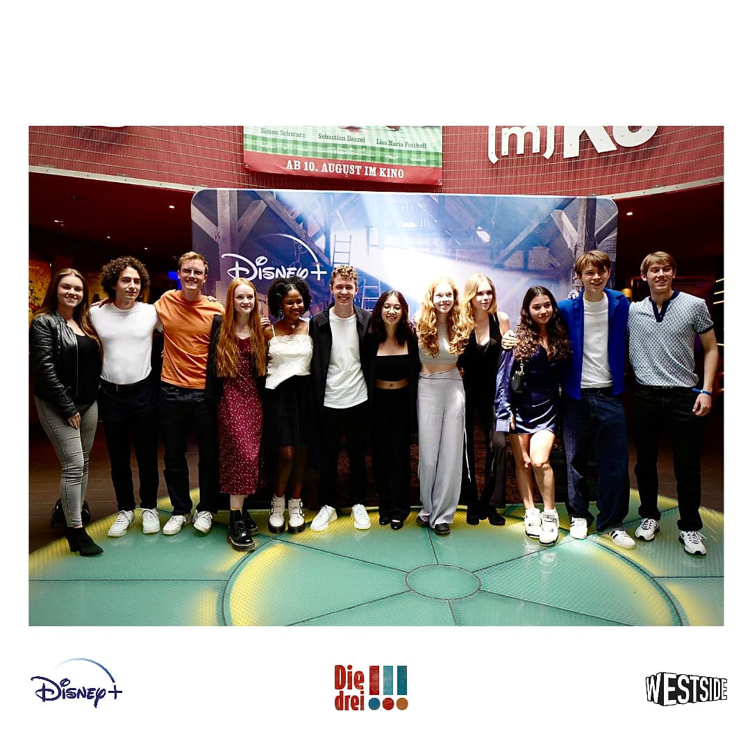Linus Moog with the ensemble at the premiere of Die drei !!! in front of the Disney+ photo wall
